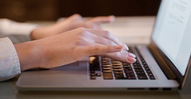 Close-up of hands typing on laptop