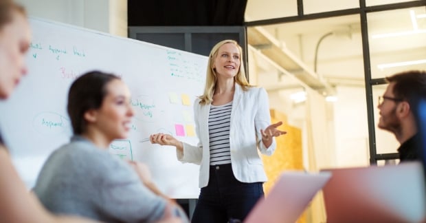 Woman speaking in meeting while standing at whiteboard